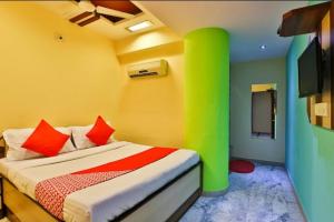 a bedroom with a bed with green and red pillows at Hotel Honey Bunny in Ahmedabad