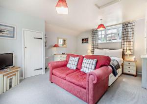 a bedroom with a red couch and a bed at Coach House Cottage Annexe in Wickham Market