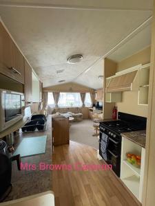 a kitchen and living room with a stove top oven at 6 Berth, pet friendly caravan with decking in Little Clacton