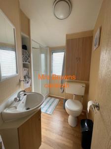 y baño con aseo blanco y lavamanos. en 6 Berth, pet friendly caravan with decking en Little Clacton