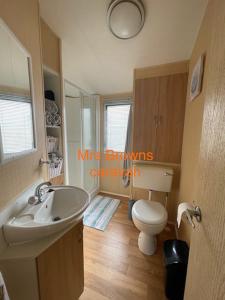 a bathroom with a white toilet and a sink at 6 Berth, pet friendly caravan with decking in Little Clacton