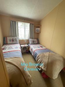 1 dormitorio con 2 camas y ventana en 6 Berth, pet friendly caravan with decking en Little Clacton