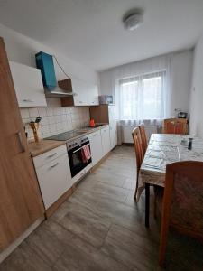 Wohnung mit 2 Zimmern في Ballenberg: مطبخ مع دواليب بيضاء وطاولة مع غرفة طعام