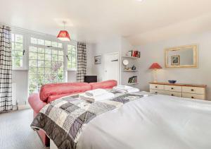 a bedroom with a white bed and a red couch at Coach House Cottage Sleeps 6 in Wickham Market