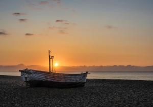 een boot op het strand bij zonsondergang bij La Ronessa in Aldeburgh