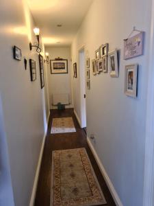 a hallway with a white wall with pictures and rugs at Coreen Guest House in Tullamore