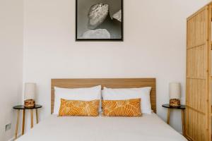 1 dormitorio con 1 cama con almohadas de color naranja y blanco en Design-led flat in Camden on quiet street, en Londres