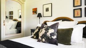 Schlafzimmer mit einem Bett mit weißen Kissen und einem Spiegel in der Unterkunft Newman House in Daylesford