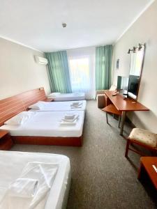 a hotel room with two beds and a desk at Hotel Green Park in Kiten