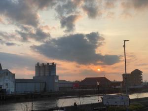 a sunset over a city with a building and water at Spacious One Bedroom Flat with River View, 1E in Great Yarmouth