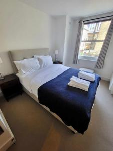 Lovely newly refurbished apartment in Battersea في لندن: غرفة نوم بسرير كبير عليها مناشف