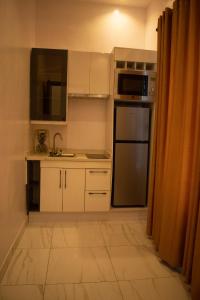 a kitchen with white cabinets and a stainless steel refrigerator at Sapphire Residences by Crystal in Ikeja