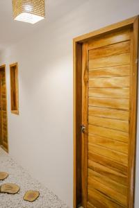 una puerta de madera en una habitación con sandalias en el suelo en Pousada Chez Ellery Jeri, en Jericoacoara