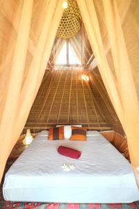 a bed in a straw tent with a window at Eco LoveBamboo in Dalung
