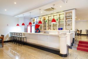 a restaurant with a counter with chairs and red lamps at Taiwan Hotel in Ribeirão Preto
