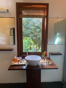 Pousada Bambu Dourado في ماراو: منضدة الحمام مع الحوض والنافذة