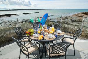 einen Tisch mit Stühlen und einen Tisch mit Essen und dem Meer in der Unterkunft Armada Cottages in Spanish Point