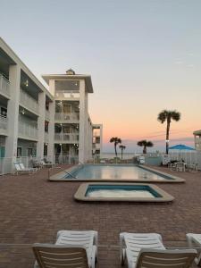 a swimming pool with chairs and a building at Coastal Waters 110 - 1 Bedroom, 1st Floor Pool Side Condo in New Smyrna Beach