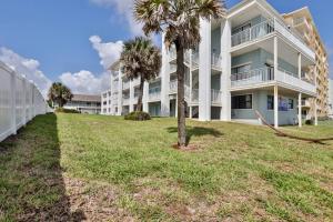 a large apartment building with palm trees in front of it at Coastal Waters 110 - 1 Bedroom, 1st Floor Pool Side Condo in New Smyrna Beach