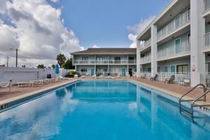 a large swimming pool in front of a building at Coastal Waters Studio 111 - Pool Side Studio in New Smyrna Beach