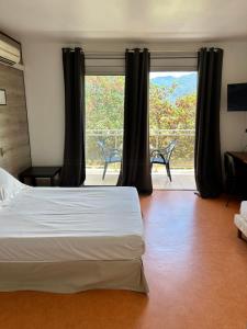 een slaapkamer met een bed en een groot raam bij HOTEL LA GARENNE in Tresserre