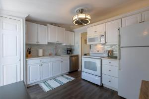 a kitchen with white cabinets and a white refrigerator at Dolphin Cove Cottage -22 & Pet Friendly! in New Smyrna Beach