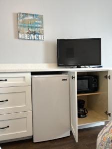 a white desk with a tv and a white refrigerator at Coastal Life 206 - A 2nd Floor Studio With 2 Single Beds in New Smyrna Beach
