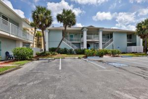 a parking lot in front of a building with palm trees at Coastal Waters Life - 2nd Floor 1 Bedroom! in New Smyrna Beach
