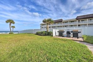 a building with palm trees in front of the ocean at Coastal Waters 108-109- 2 Bedroom 2 Bath Pool Side Condo! in New Smyrna Beach
