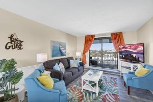 a living room with a couch and chairs and a tv at The Sea Esta At Coastal Waters in New Smyrna Beach