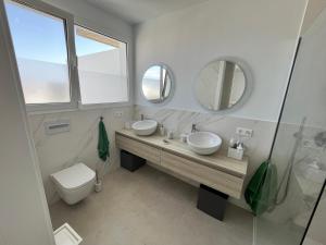 a bathroom with two sinks and a toilet and a mirror at Casa el Timple in Costa Teguise