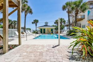 a swimming pool with palm trees and a building at Ocean Club At Turtlemound 107 - 2 Bedroom 1 Bath in New Smyrna Beach