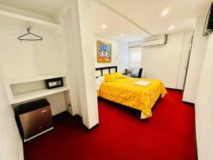 1 dormitorio con cama amarilla y alfombra roja en Le Prince Arica, en Arica