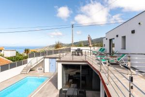 a house with a balcony with a swimming pool at Casa Santi Stefany in Arco da Calheta