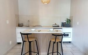 una cucina con bancone e 2 sgabelli da bar di Lemon Tree Manor - Scandi Suite a Groblersdal