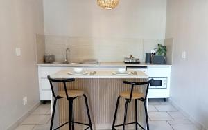 a kitchen with a counter and two bar stools at Lemon Tree Manor - Scandi Suite in Groblersdal