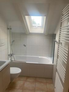 ein Badezimmer mit Badewanne und Toilette und einem Fenster in der Unterkunft Ferienwohnung Königsschloss in Schwangau + 14 Fotos