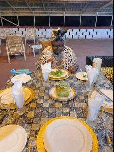 Eine Frau, die an einem Tisch mit Teller Essen sitzt. in der Unterkunft CASA in Cape Coast