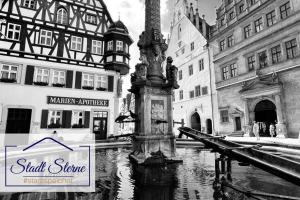 a black and white photo of a water fountain in a city at #Stadtspeicher - Grüner Stern das Apartment mitten in der Altstadt in Rothenburg ob der Tauber