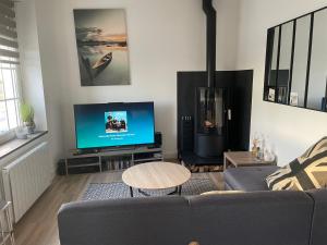 sala de estar con sofá y TV de pantalla plana en La maison sur la plage, en Marennes