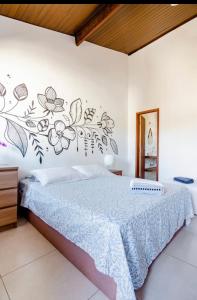 1 dormitorio con 1 cama con flores en la pared en Suítes Astral, en Búzios