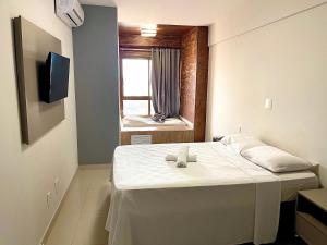 un letto bianco in una stanza con finestra di DUPLEX com Hidromassagem total de 02 QUARTOS e Vista MAR ad Aracaju