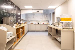 a large kitchen with white cabinets and counters at Hotel Dom Rafael Executivo in Santa Maria
