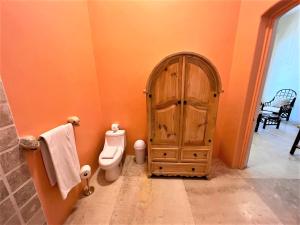 un bagno arancione con servizi igienici e porta in legno di Villa Amor a Sayulita
