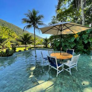 a table and chairs with an umbrella next to a pool at Complexo Ubatubinha in Angra dos Reis