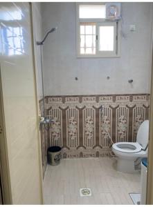 a bathroom with a toilet and a window at شقة مفروشه ب٣ غرف in Sūq al Aḩad