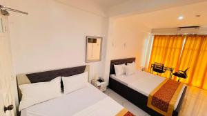 a hotel room with two beds and a window at Legends Hotel & Events Hall - Lemery & Taal in Lemery