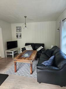 uma sala de estar com um sofá de couro e uma mesa de centro em Trivelig hus sentralt på Storslett em Storslett