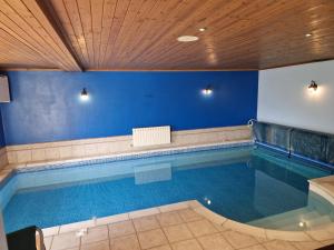 - une grande piscine dans une pièce aux murs bleus dans l'établissement 5 Bedroom Holiday Home With Spa Now Available, à Tenby