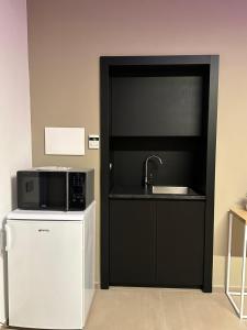 eine Küche mit einer Mikrowelle, einer Spüle und einem Kühlschrank in der Unterkunft MP Luxury room in Budoni